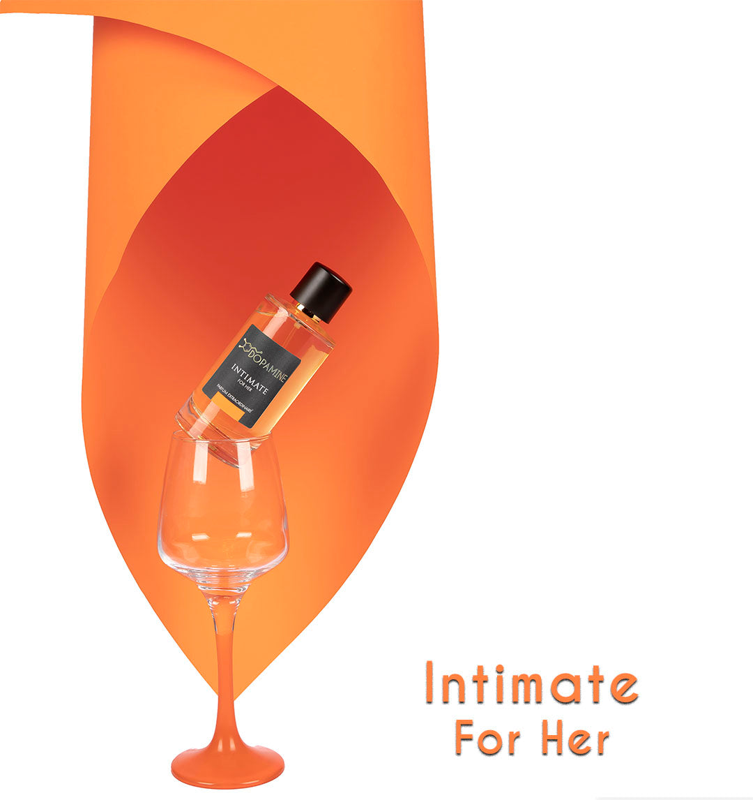 A bottle of Dopamine Intimate Perfume for Women kept in a wine glass with orange base and artistically enveloped on three sides by an orange paper