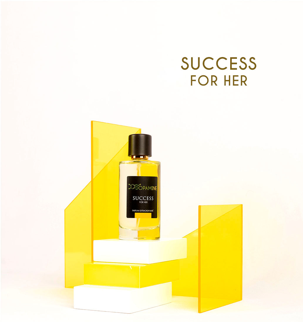 Bottle for Dopamine Perfume Success for her standing against a artistic design of yellow transparent sheets